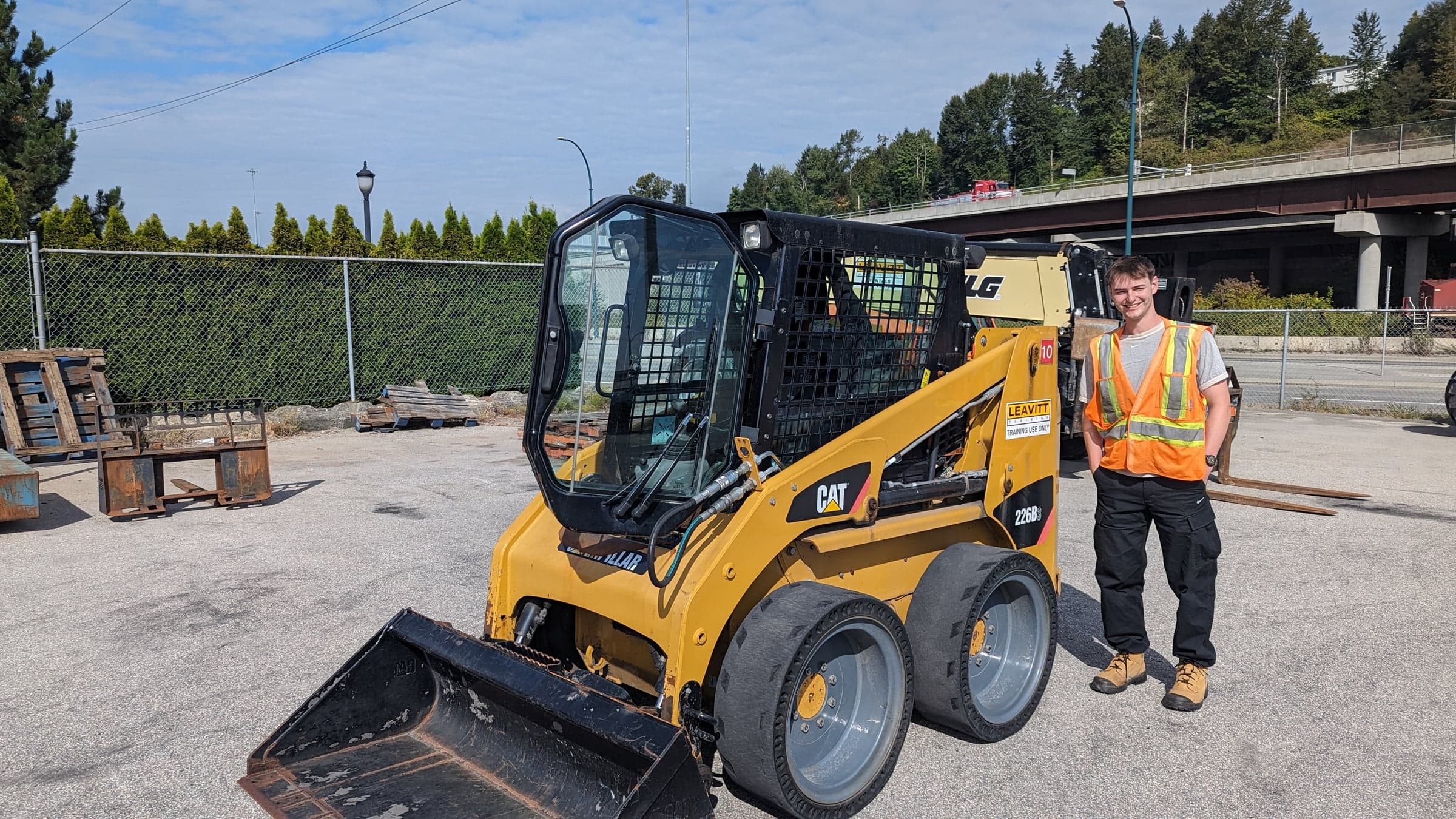 Ethan in hi vis beside a Leavitt training skid steer